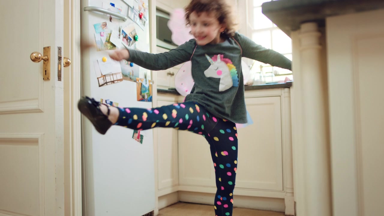Young Girl Wearing Fairy Wings Dancing in Kitchen