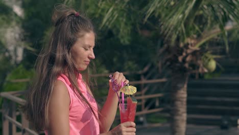 attractive woman in pink shirt drinks watermelon cocktail