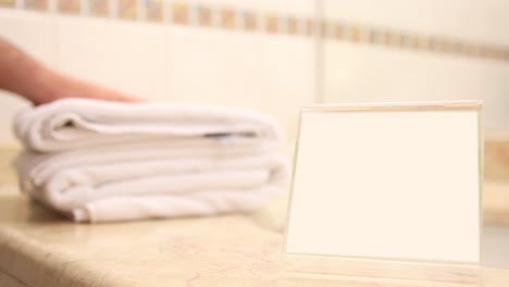 disparo en primer plano de la ama de llaves colocando toallas de baño limpias en el baño con tarjeta clave de cromo