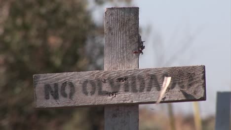 An-old-dirty-wooden-cross-with-the-marking-No-Olvidado-is-shown-with-weeds-growing-near-it-blowing-in-the-wind