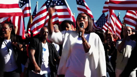 woman speaking at a patriotic rally surrounded by american flags