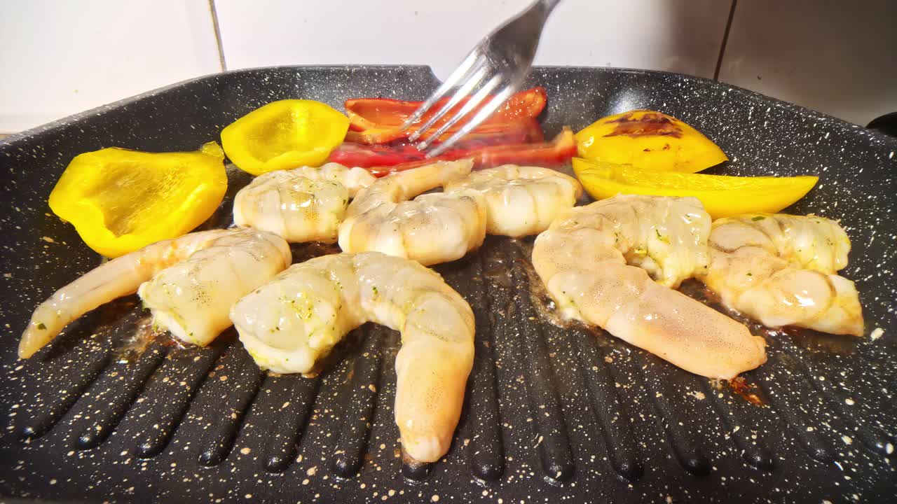 Shrimp and peppers grilling on a sizzling hot pan with fork adjustment