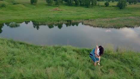 Vista-Superior-Del-Hombre-Con-Chaleco-Vaquero-Y-Pantalones-Cortos-Gira-A-La-Chica-Junto-Al-Lago