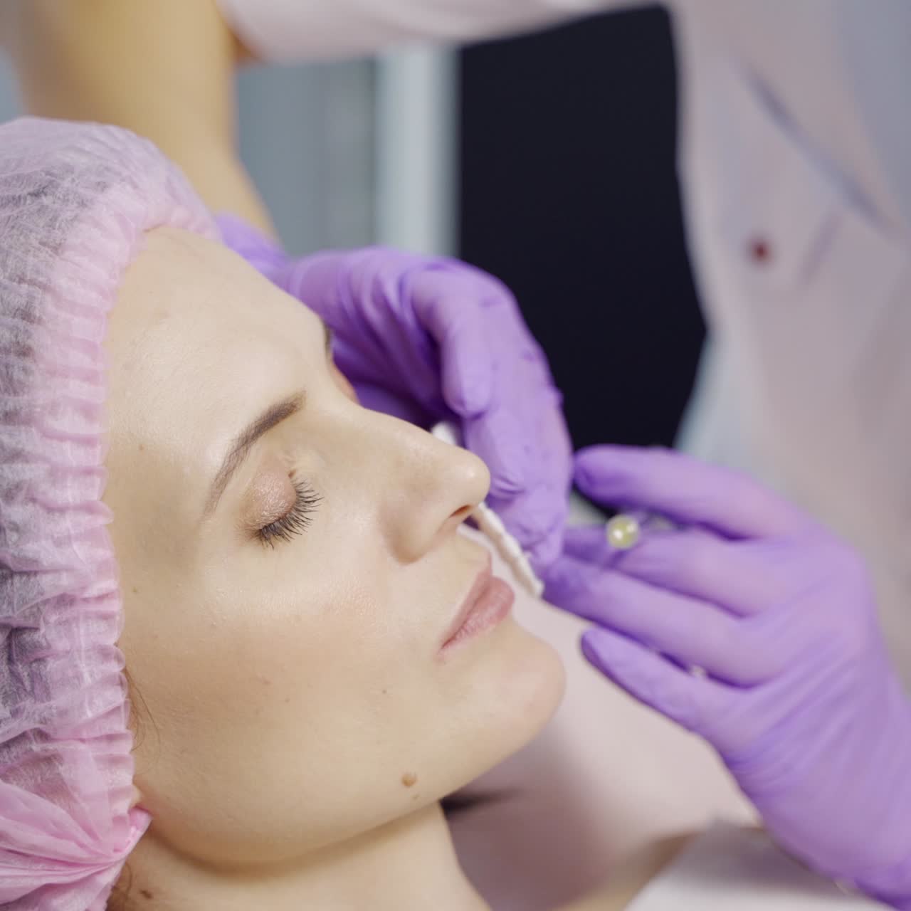 A specialist in aesthetic cosmetology holds a syringe in her hand and makes Botox injections to the lips for the client. Close-up.
