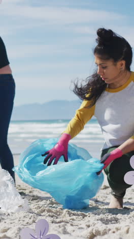 animation of flowers over diverse female and male volunteers picking up rubbish on beach