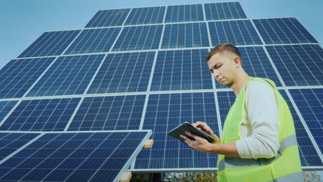 a worker uses a tablet in a large ground-based solar panel alternative energy