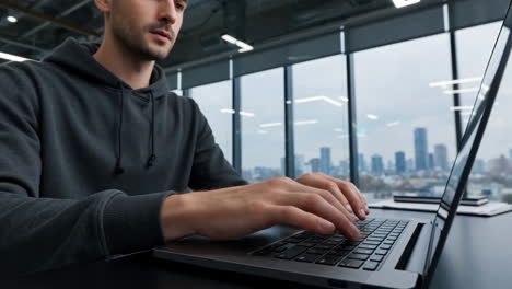 man working on laptop with holographic data display in office