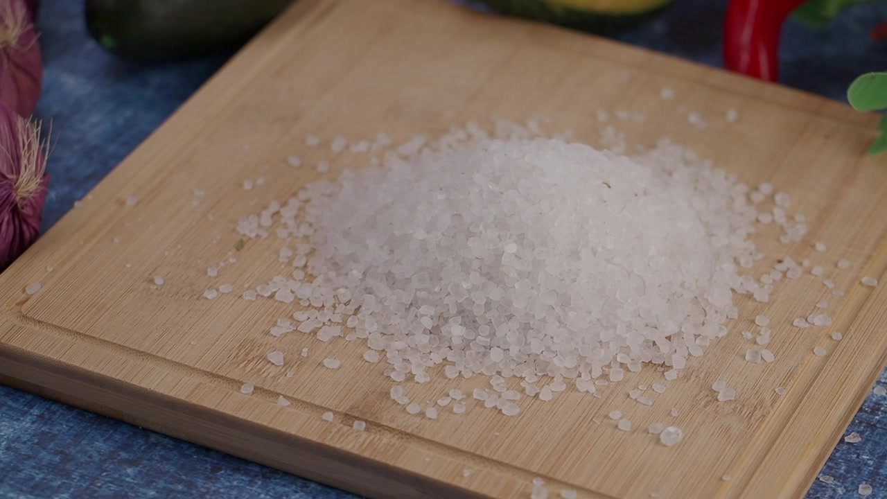 Close-up garam laut kasar di atas talenan kayu dengan bawang putih dan cabai