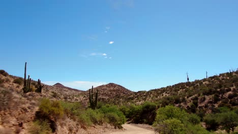 4K-Drohne,-Die-Mit-Dem-Auto-Auf-Der-Unbefestigten-Straße-In-Der-Wüste-Von-Arizona-Vorbeifährt