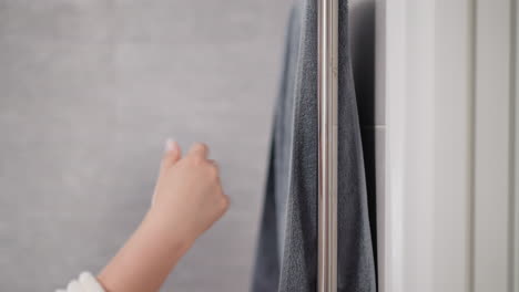 female with manicure dries hand using bath towel after taking shower. person dries hand with hanging towel on handrail in shower slow motion