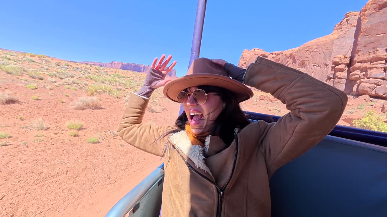 Šťastná žena jedoucí v otevřeném vozidle pouští Monument Valley