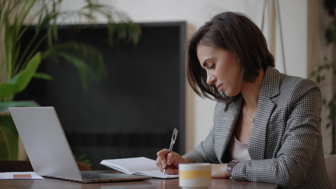 mujer de negocios analizando el gráfico y escribiendo en el portátil. trabajo remoto mujer joven con gafas escribe notas en el portapapeles y escribiendo en el teclado del portátil
