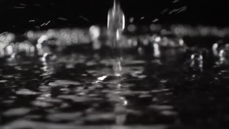 captivating water droplets dance on a dark surface: a visual exploration of fluid dynamics and reflections in motion