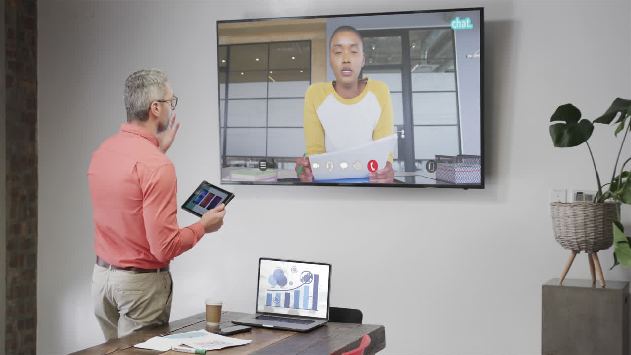 Caucasian businessman on video call with african american male colleague on tv screen