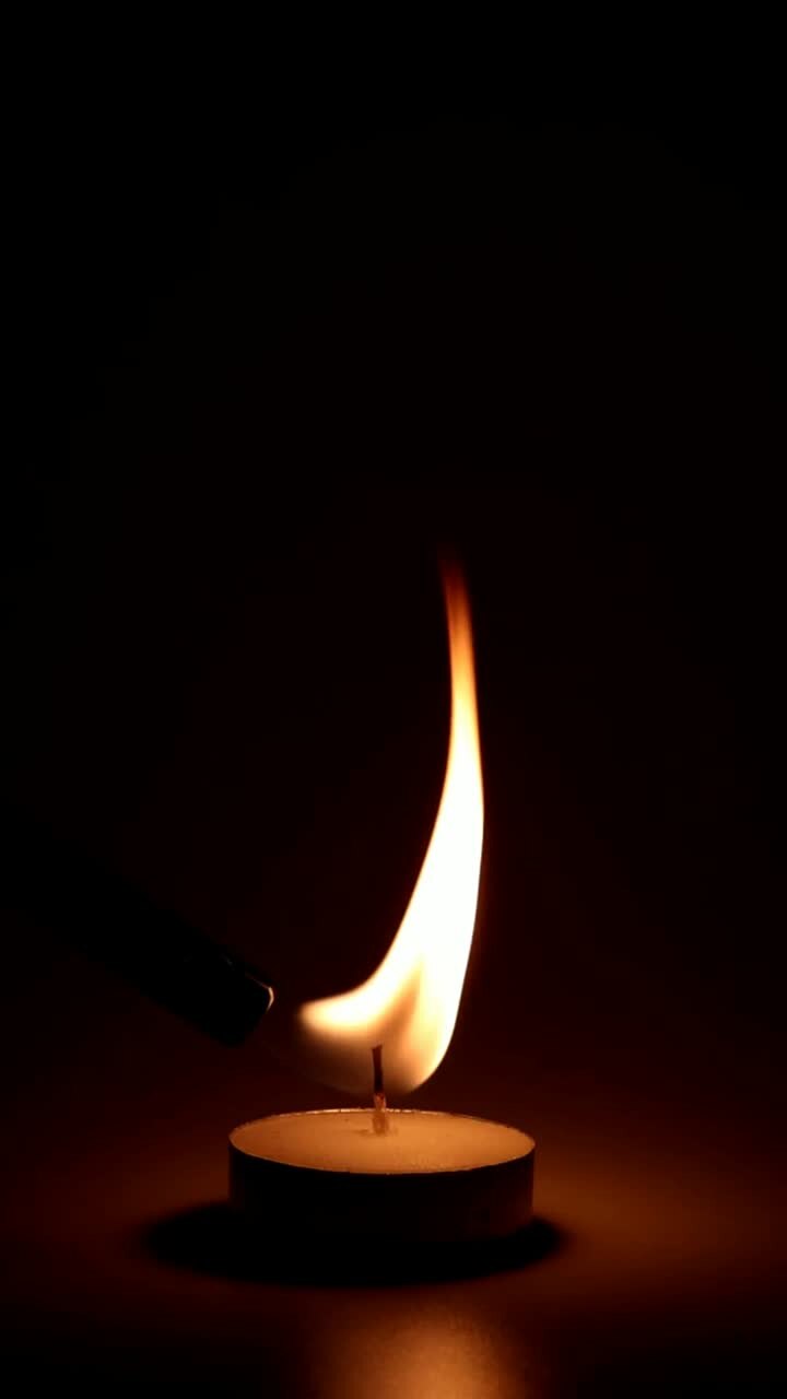 eine einzige kerze brennt und flackert im dunkeln