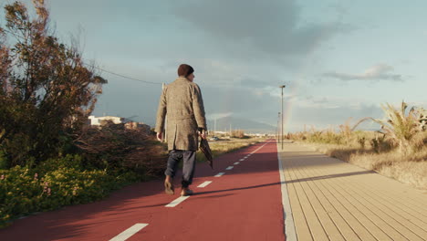 elderly man walks on the bike lane holding an umbrella