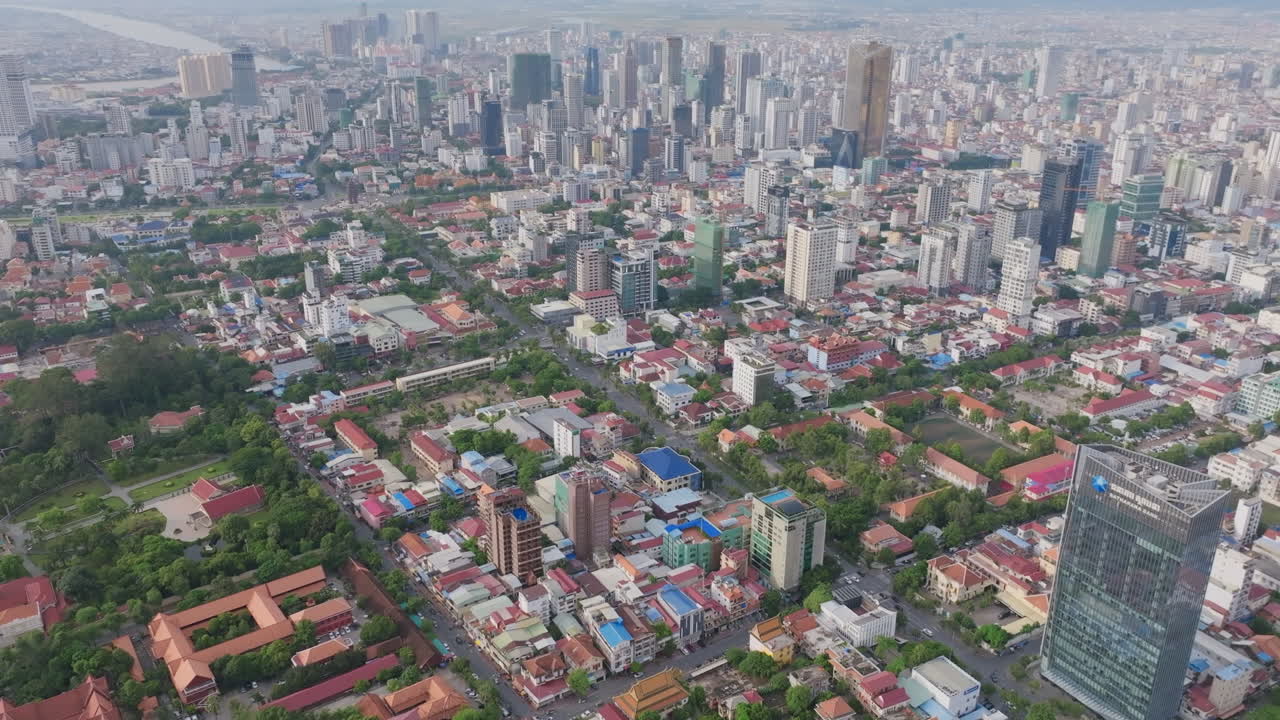 Aerial video of Phnom Penh shows the Royal Palace complex surrounded by greenery in the foreground, with a dense city skyline stretching out behind it