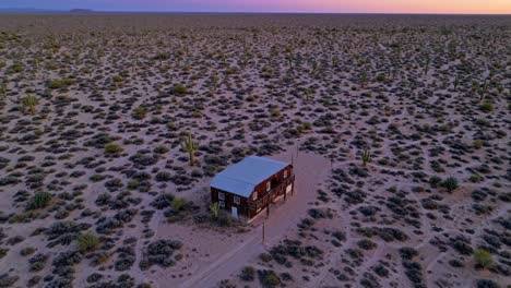 aerial view of a remote house in the arizona desert surrounded by cacti and shrubs, bathed in the warm glow of the setting sun, creating a serene and captivating scene