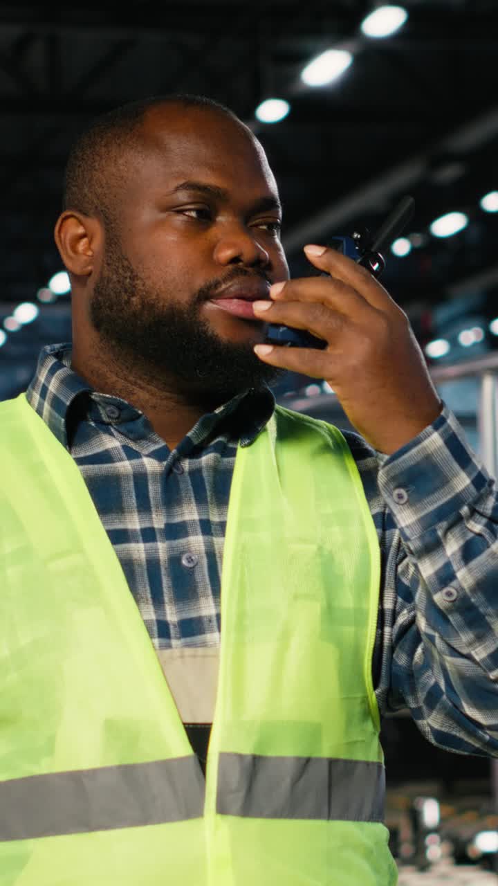 Vertical Video Black manufacturing employee uses walkie talkie to speak with supervisor