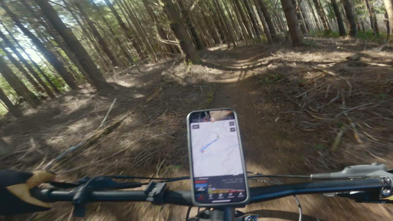 ciclismo de montaña a través de densos bosques en el noroeste del pacífico con un teléfono inteligente montado en la bicicleta para la navegación