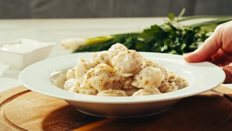 plate of pelmeni dumplings with sour cream and herbs