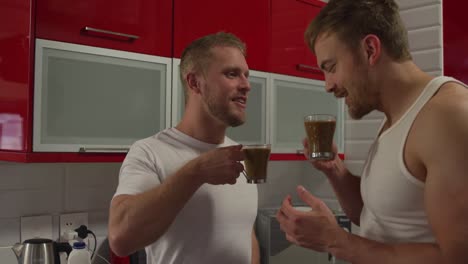 caucasian male couple in social distancing drinking coffee at home