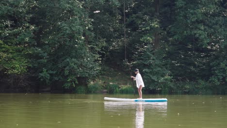 active female paddle on stand up board and wave with hand, czech republic