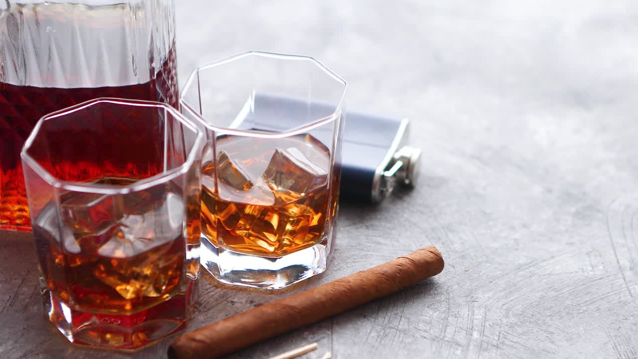 Two glasses of old whiskey with cuban cigar and carafe