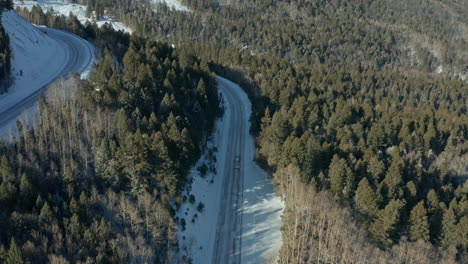 Aerial-following-truck-down-remote-mountain-road-in-winter