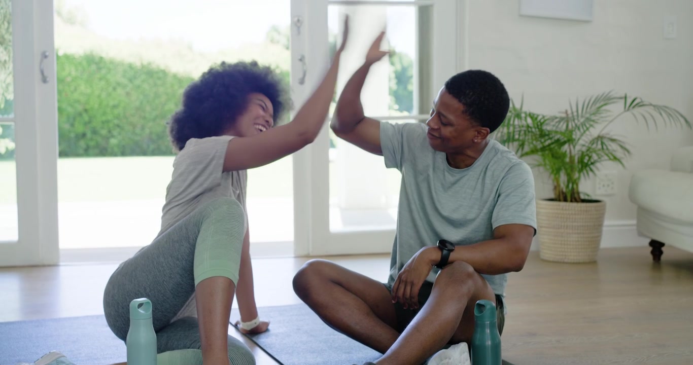 African American couple showing phone laughing pointing opening reusable bottles to hydrate at home
