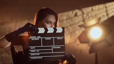 woman holding clapperboard in movie studio