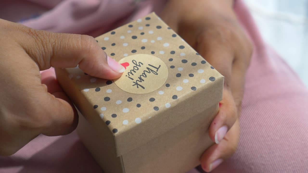 '감사' 스티커 를 붙인 선물 상자 를 받는 사람