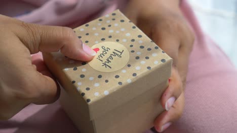 person receiving a gift box with 'thank you' sticker