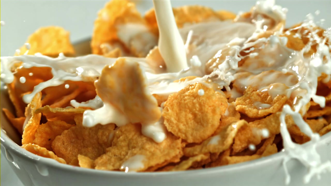 Latte che si versa in una ciotola di cornflakes in slow motion