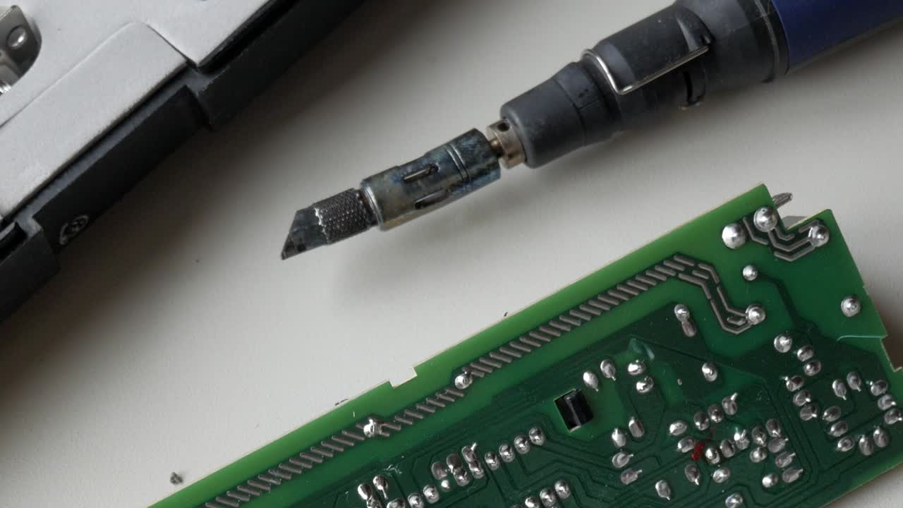 Soldering iron working on a printed circuit board, close-up of electrical components