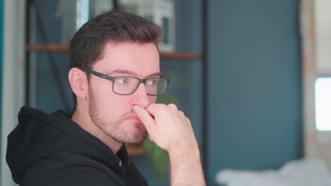 Pensive-young-man-sitting-pondering-in-living-room