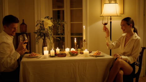 smiling pair clinking wine glasses candles table closeup. happy lovers toasting