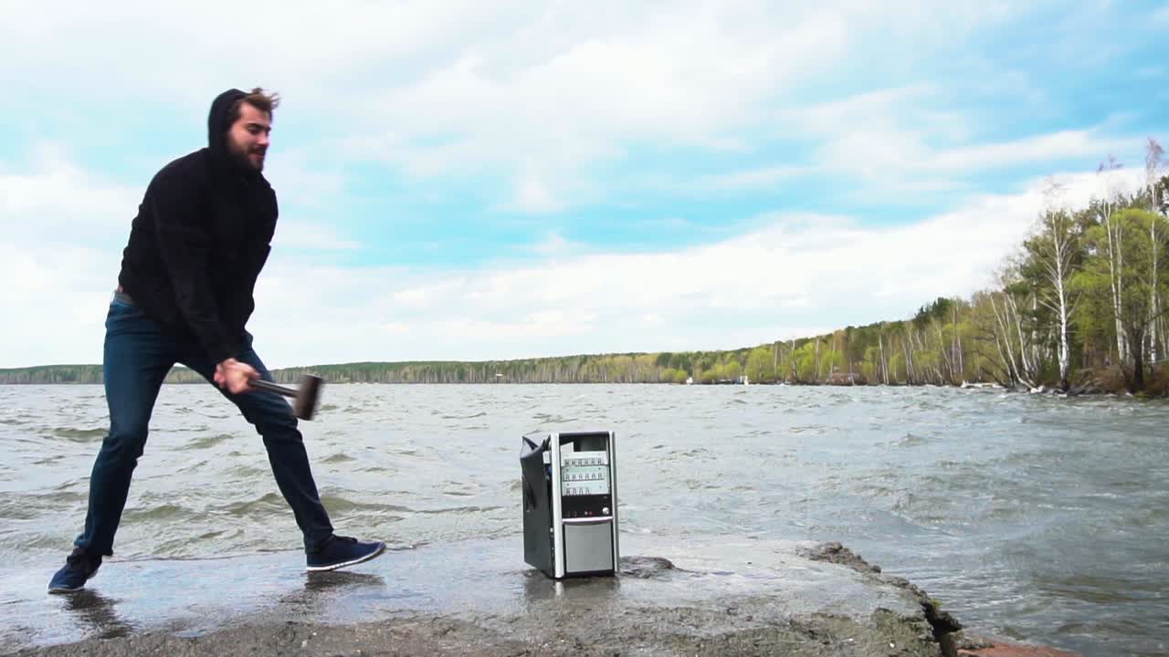 한 남자가 호수 에서 컴퓨터를 부수고 있다.