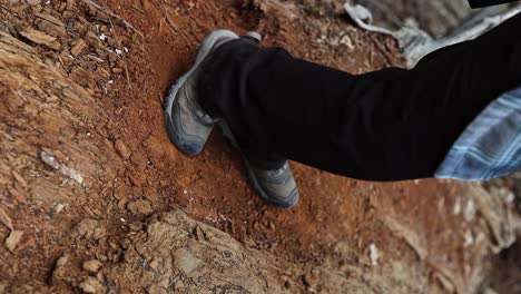 feet-in-hiking-boots-stomping-and-rubbing-woodchips-and-dirt-with-red-tones-VERTICAL