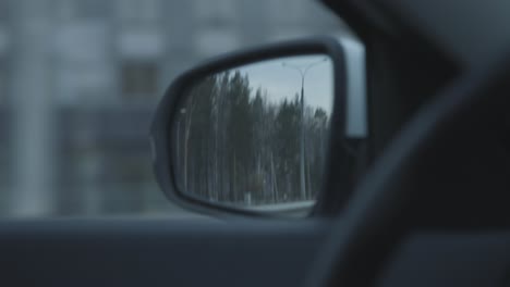 car side mirror view of road and trees