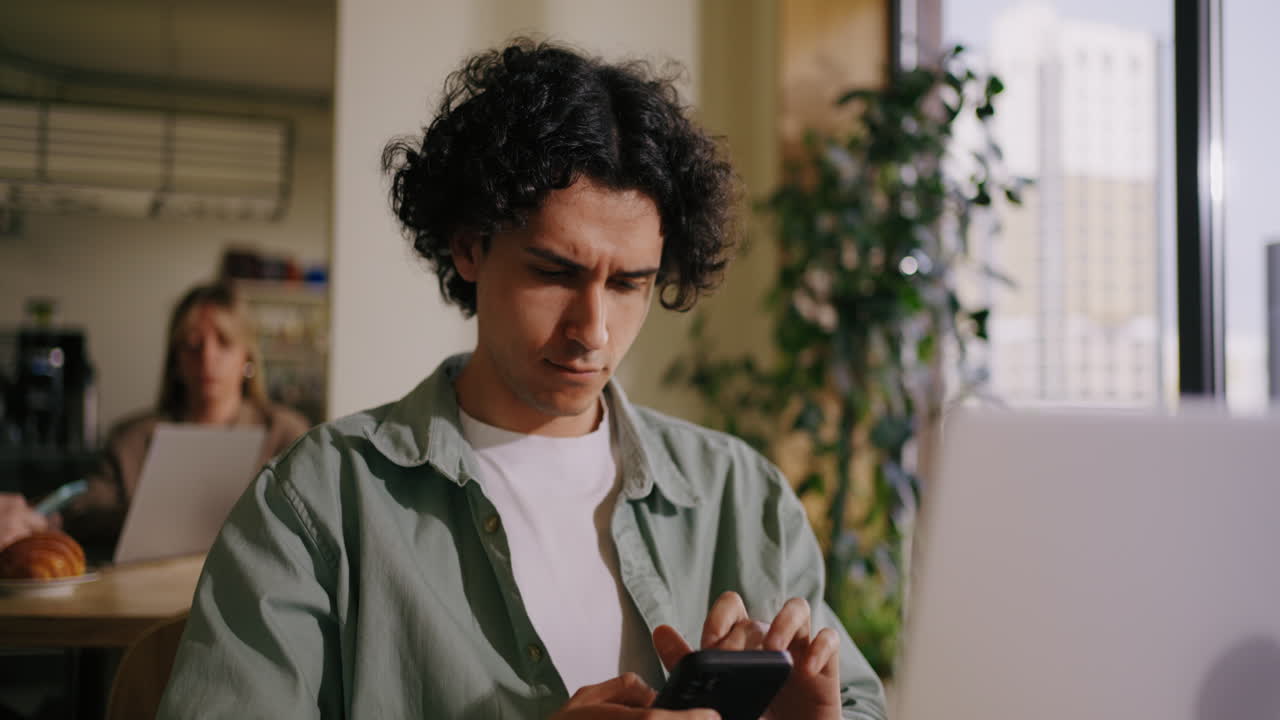 Man and Woman Sitting in Cafe Working on Laptop and Phone