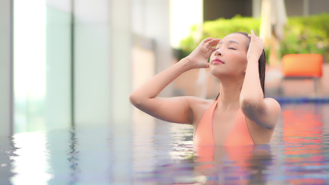 리조트 수영장에서 미디엄 클로즈의 아름다운 여성이 젖은 머리를 뒤로 빗는다