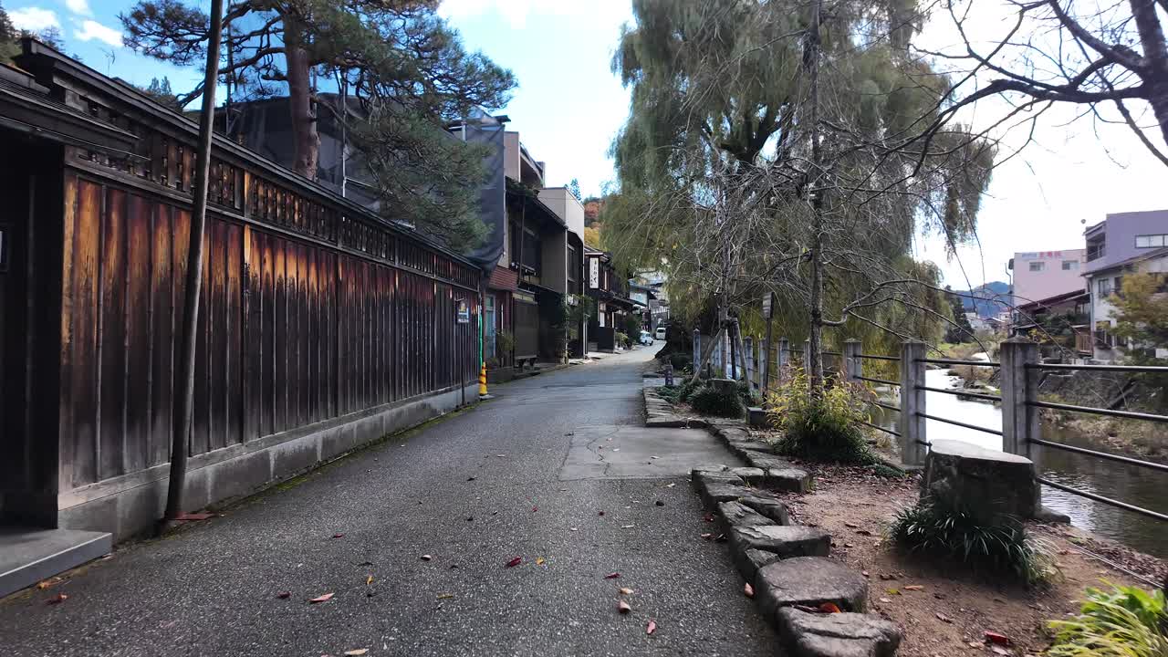 Paved street running beside Miyagawa River with traditional Japanese houses and wooden fences in Takayama, Japan