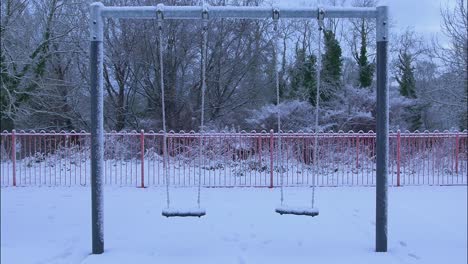 Zwei-Schaukeln-Wiegen-Sich-Bei-Schnee-Auf-Einem-Ländlichen-Spielplatz-Sanft-In-Der-Brise