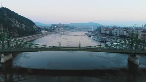 aerial view of liberty bridge on river danube in budapest at sunrise, morning, backward movement