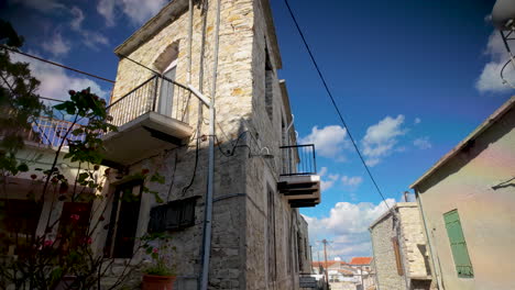 una casa de piedra alta y tradicional con balcones y un fondo de cielo azul
