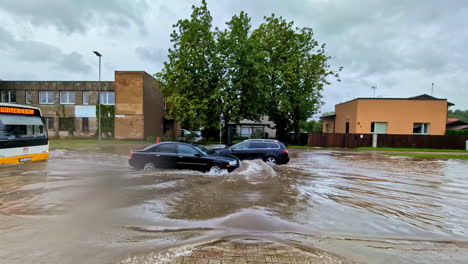cars driving through a flooded street after heavy rain in a quiet neighborhood during the day
