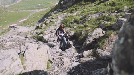 a young woman hiker climbs mountains with photo camera. transfagarasan, carpathian mountains in romania