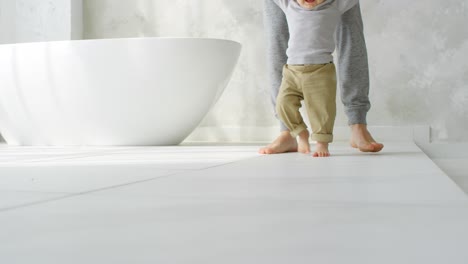 legs of baby making his first steps with help of his father at home