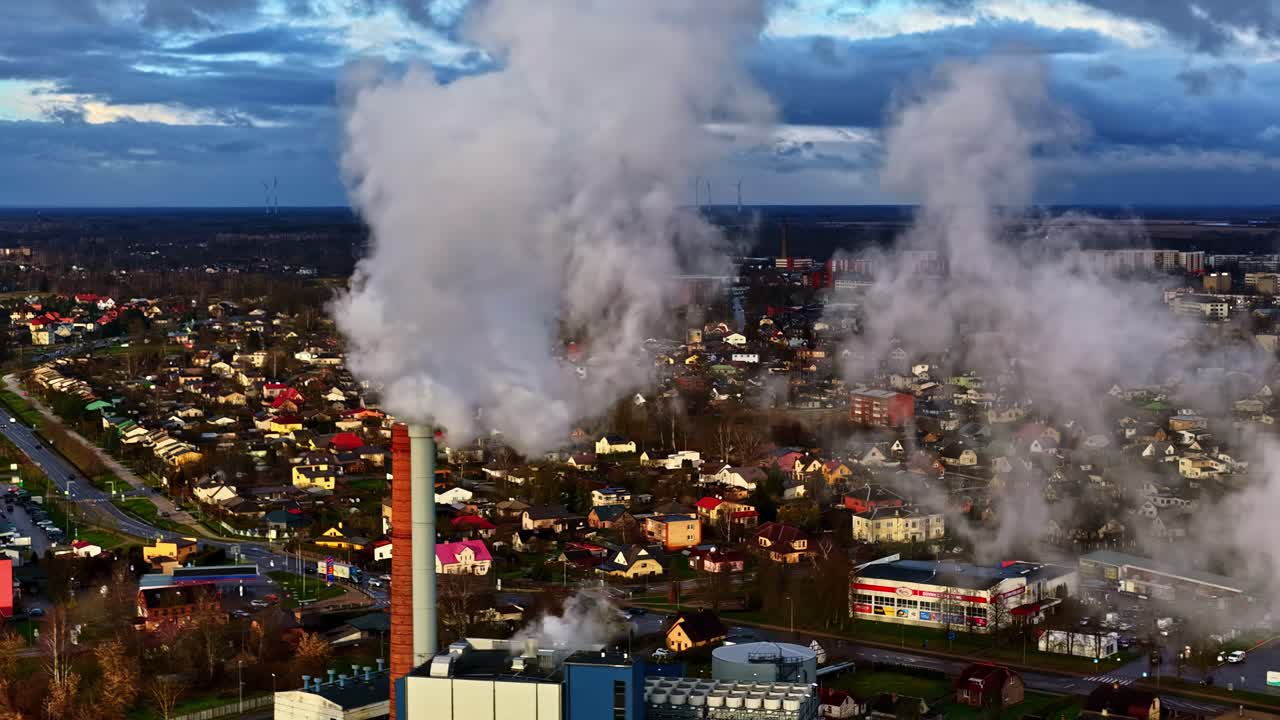Vista aerea di un impianto industriale con fumo bianco che fuoriesce da alti camini sopra lo skyline della città di Jelgava in una giornata invernale in Lettonia